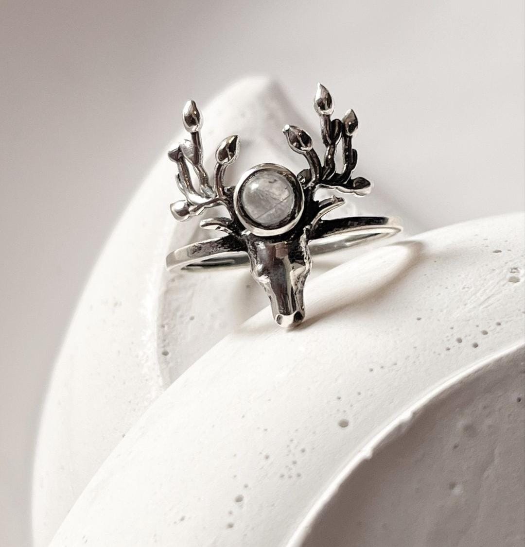 Sleek silver antler ring with a luminous moonstone centerpiece.