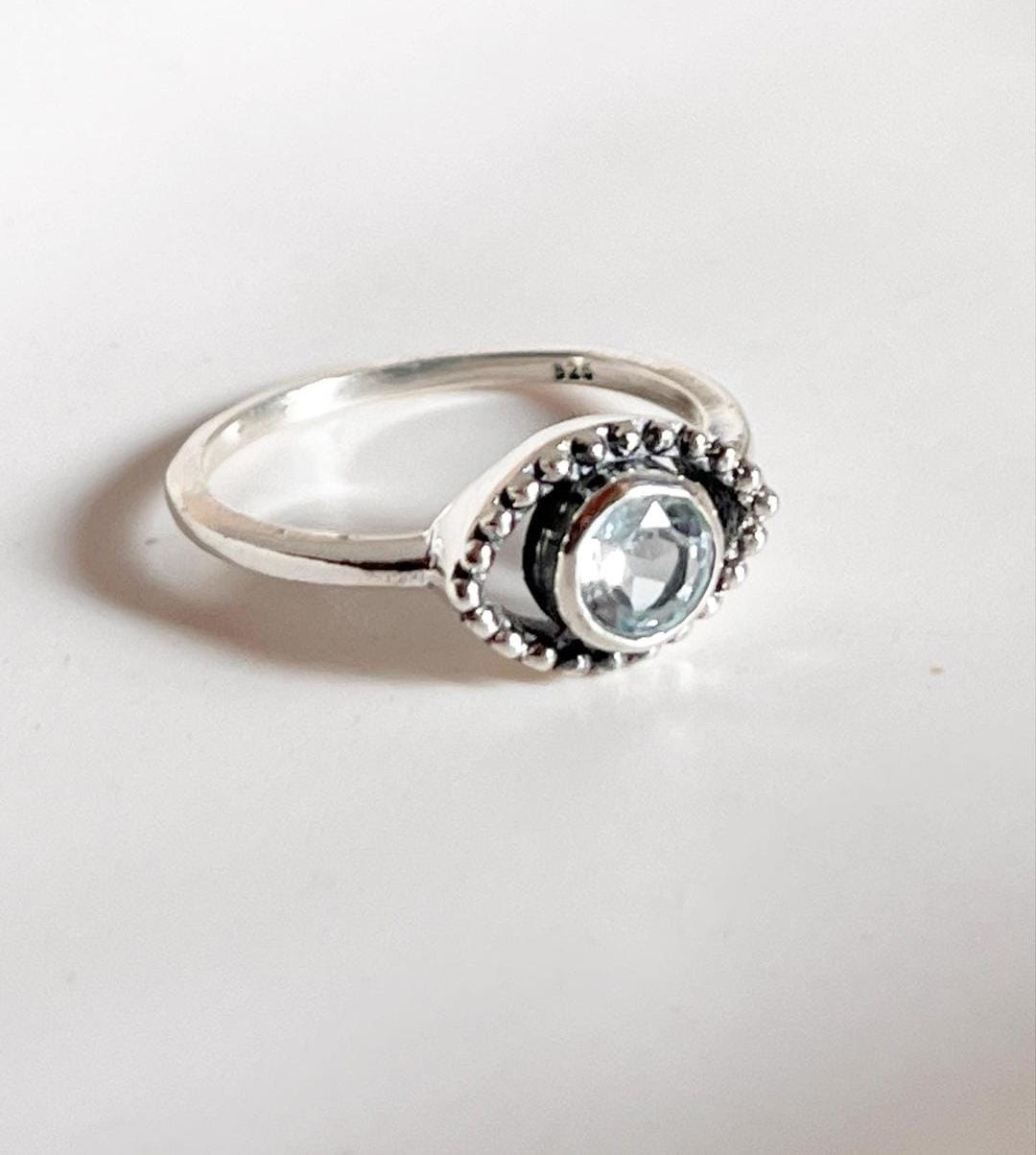 Boho-inspired evil eye silver ring with eye-catching blue topaz gemstone