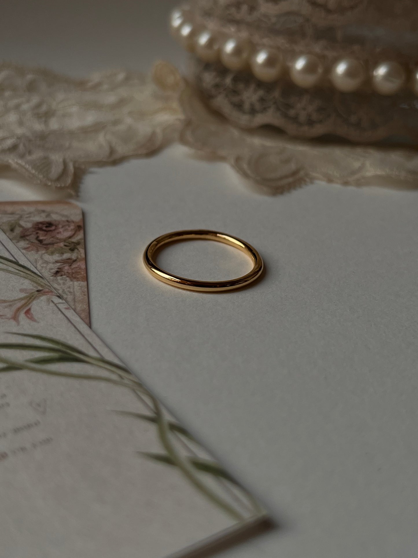 Gold vermeil plain round stack band ring placed on soft fabric with floral stationery.
