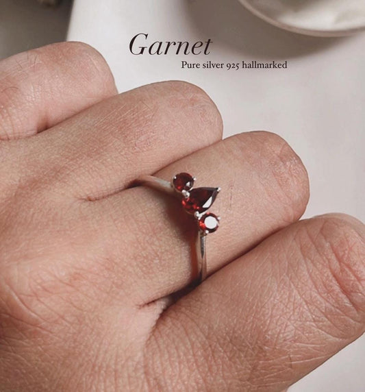 Silver ring featuring three garnet stones with pear and round cuts