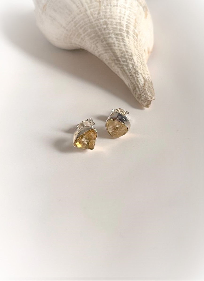 Close-up of raw uncut citrine stones set in silver stud earrings