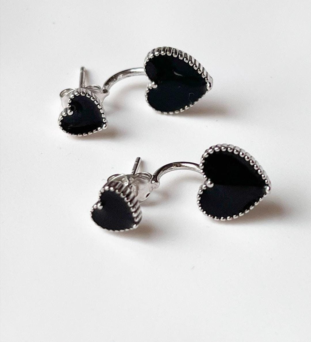 Bold silver studs with black heart enamel for a fashionable look.