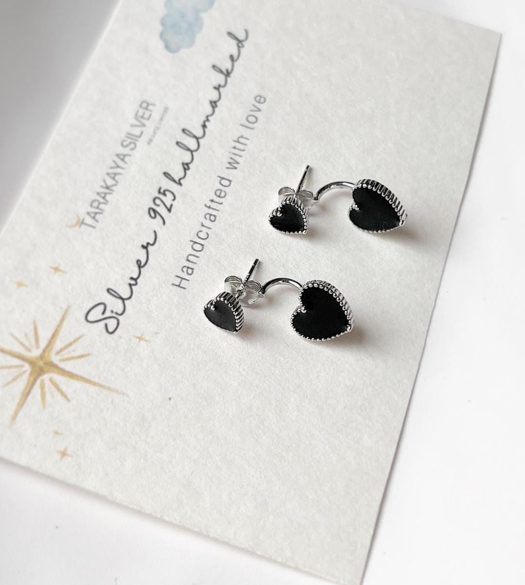 Elegant black heart enamel silver studs with sleek design.
