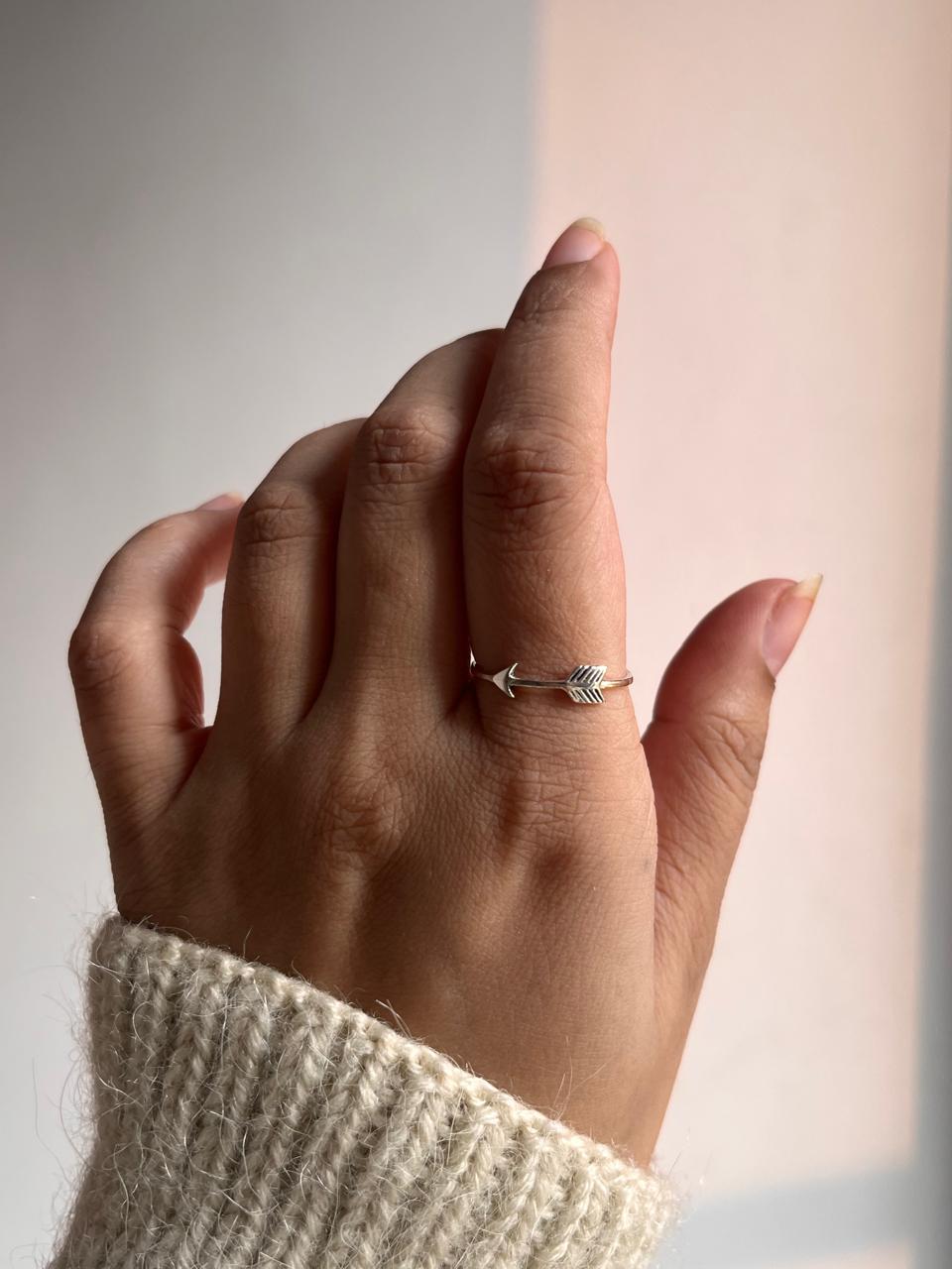Minimalist silver band ring with arrow-inspired design.