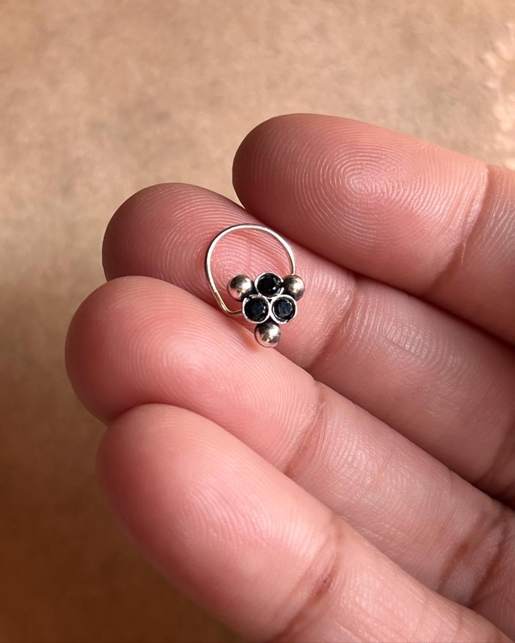 Close-up of handcrafted silver nose pin with black cubic zirconia