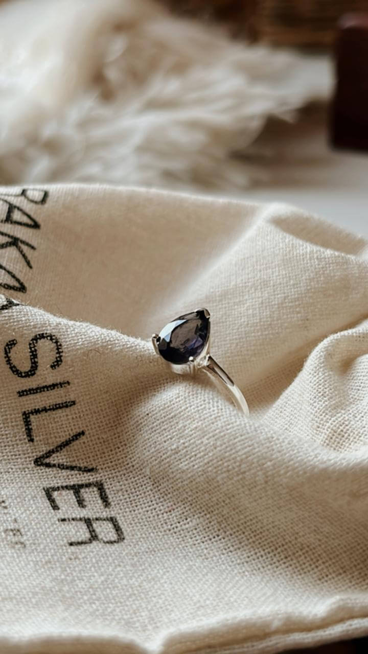 Close-up of Iolite Solitaire Pear Silver Ring on a white background
