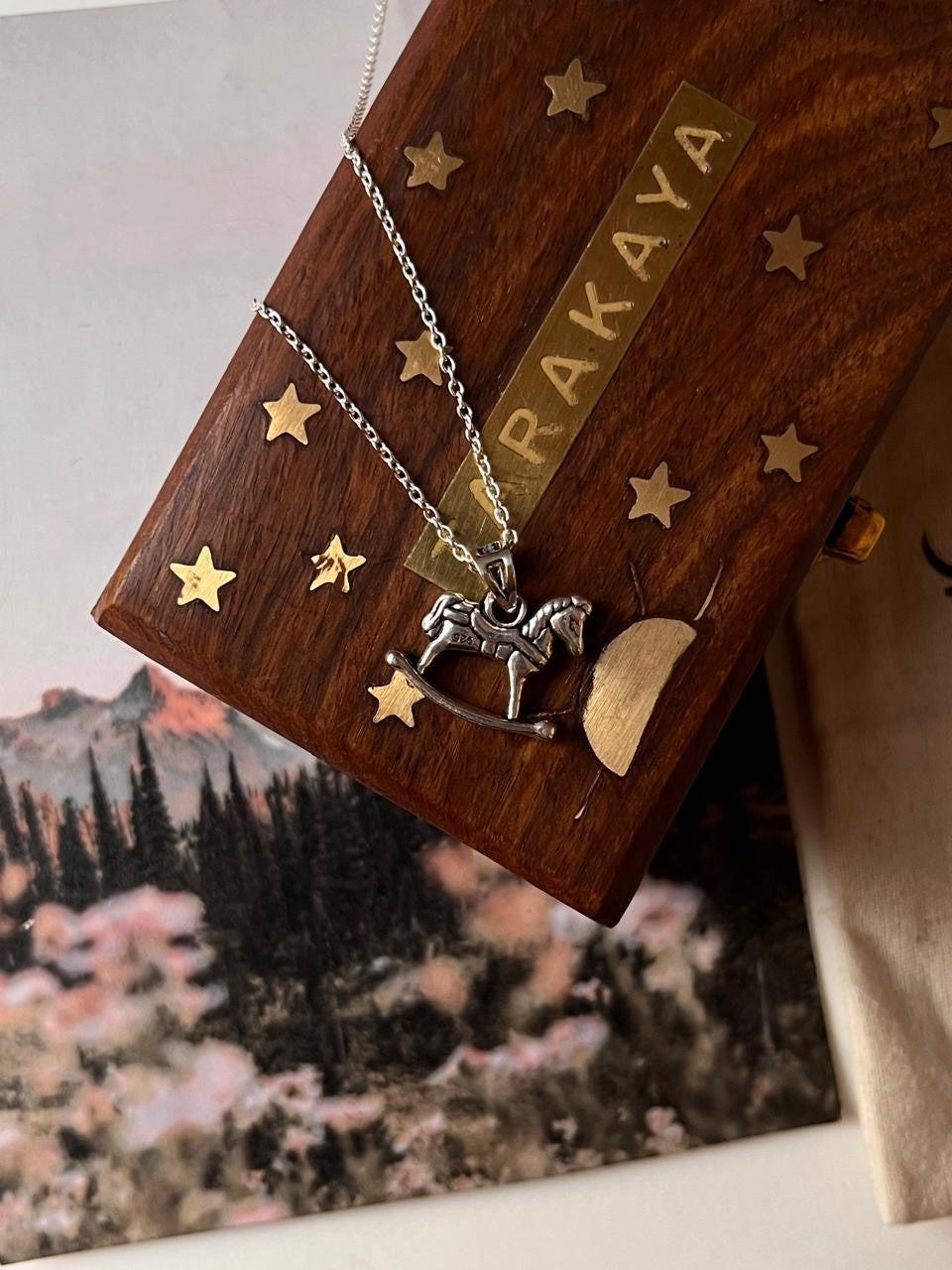Horse silver pendant on a decorative gift box with stars, highlighting unique handmade gifts.