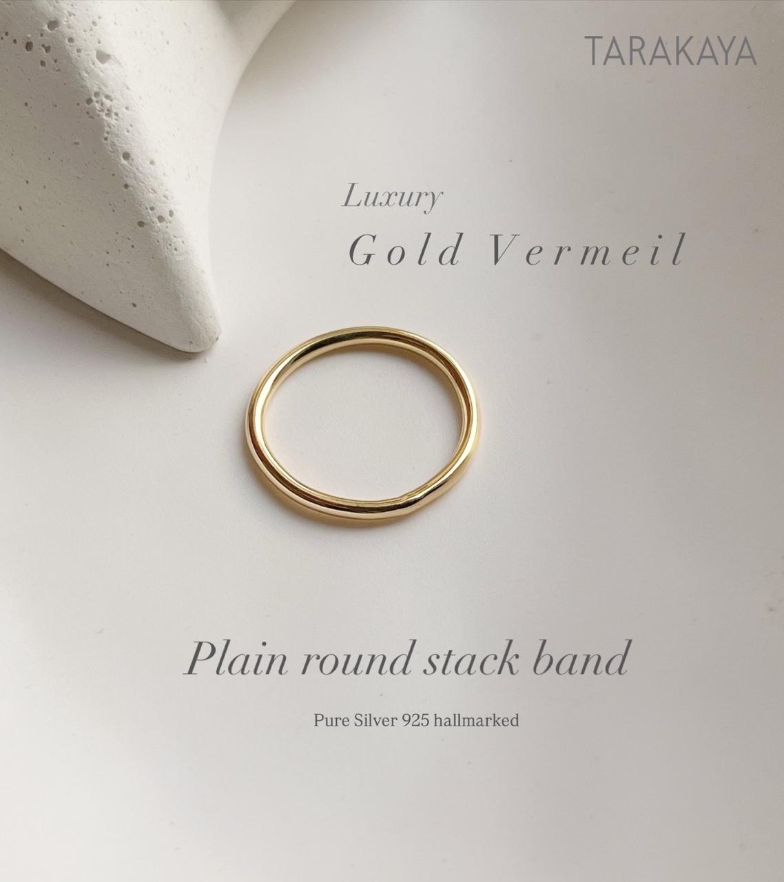Gold vermeil plain round stack band ring on textured background, highlighting its luxury and durability.