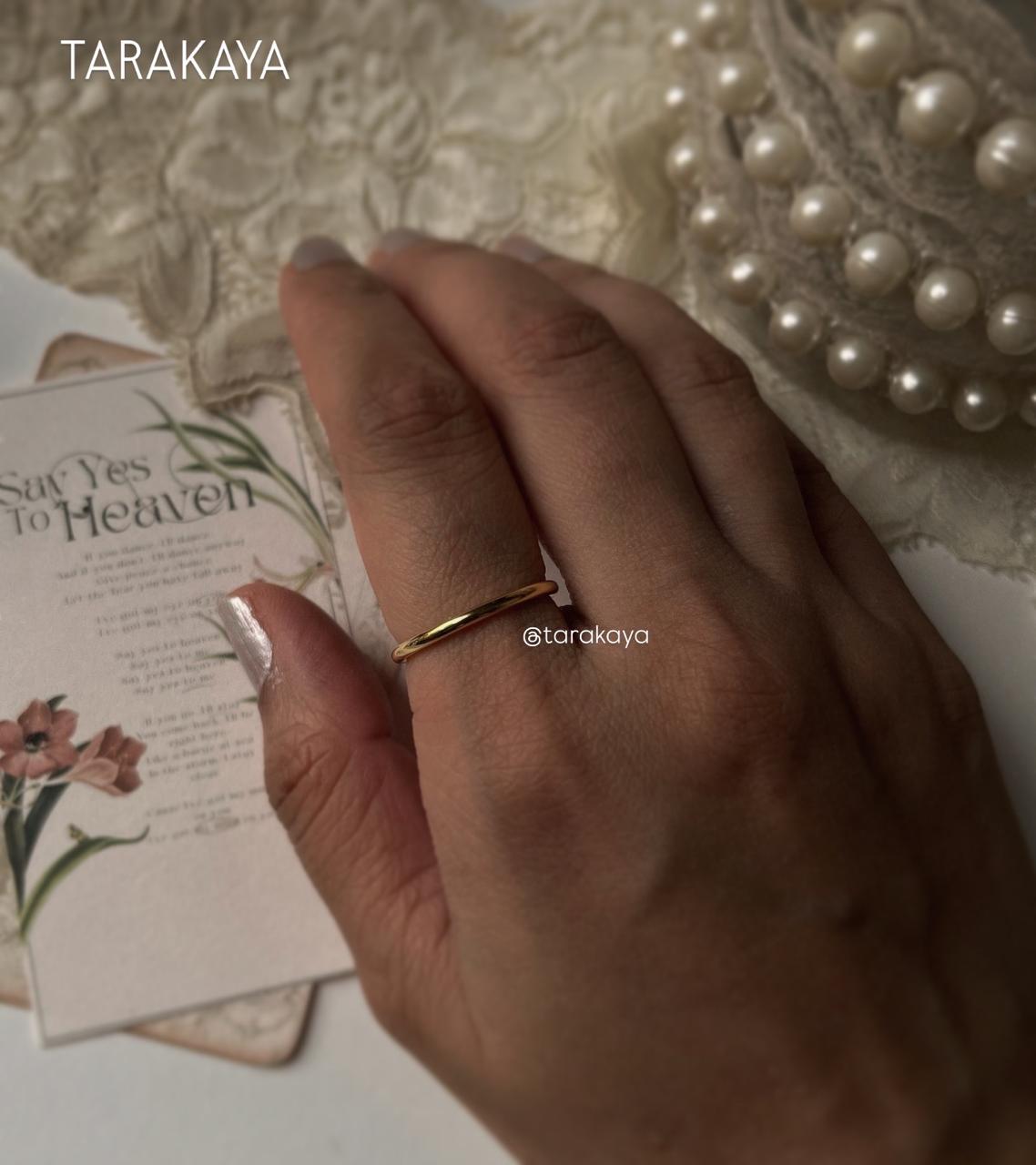 Gold vermeil plain round stack band ring on a hand, styled with floral card and pearl necklace.