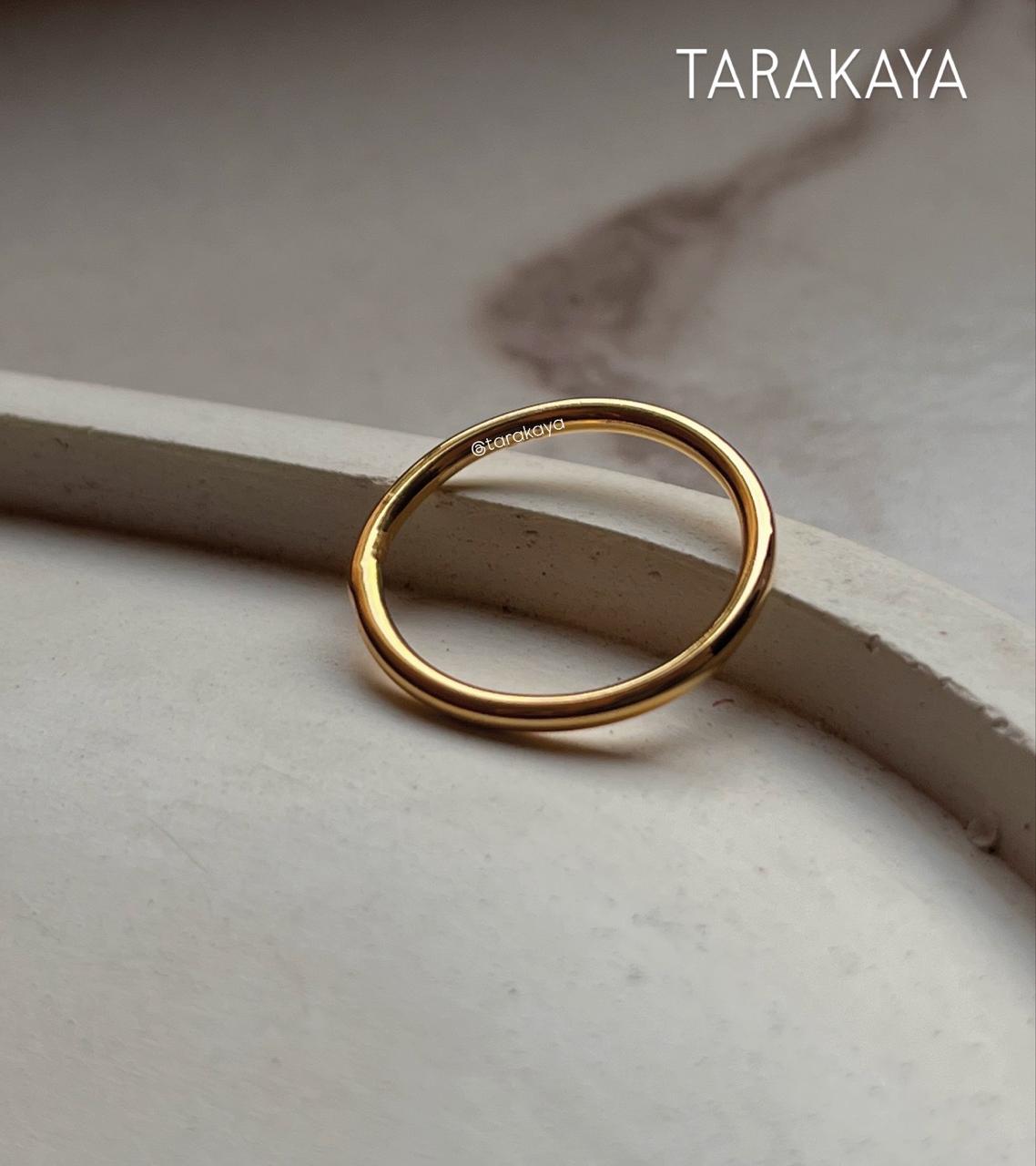 Gold vermeil plain round stack band ring on a marble surface, showcasing its elegant minimalist design.