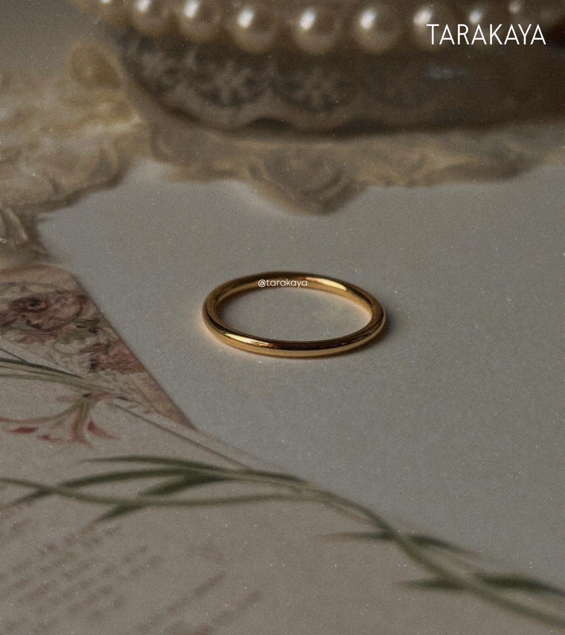 Gold vermeil plain round stack band ring on a soft surface with floral design, showcasing its shine and elegance.