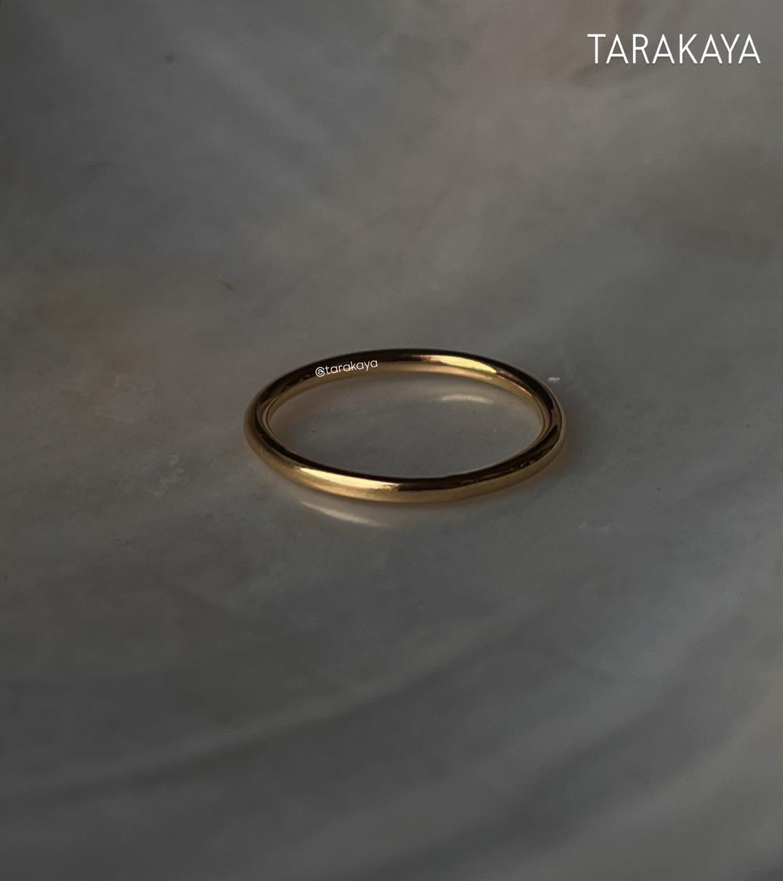 Gold vermeil plain round stack band ring on a marble surface, showcasing its elegant design and durability.