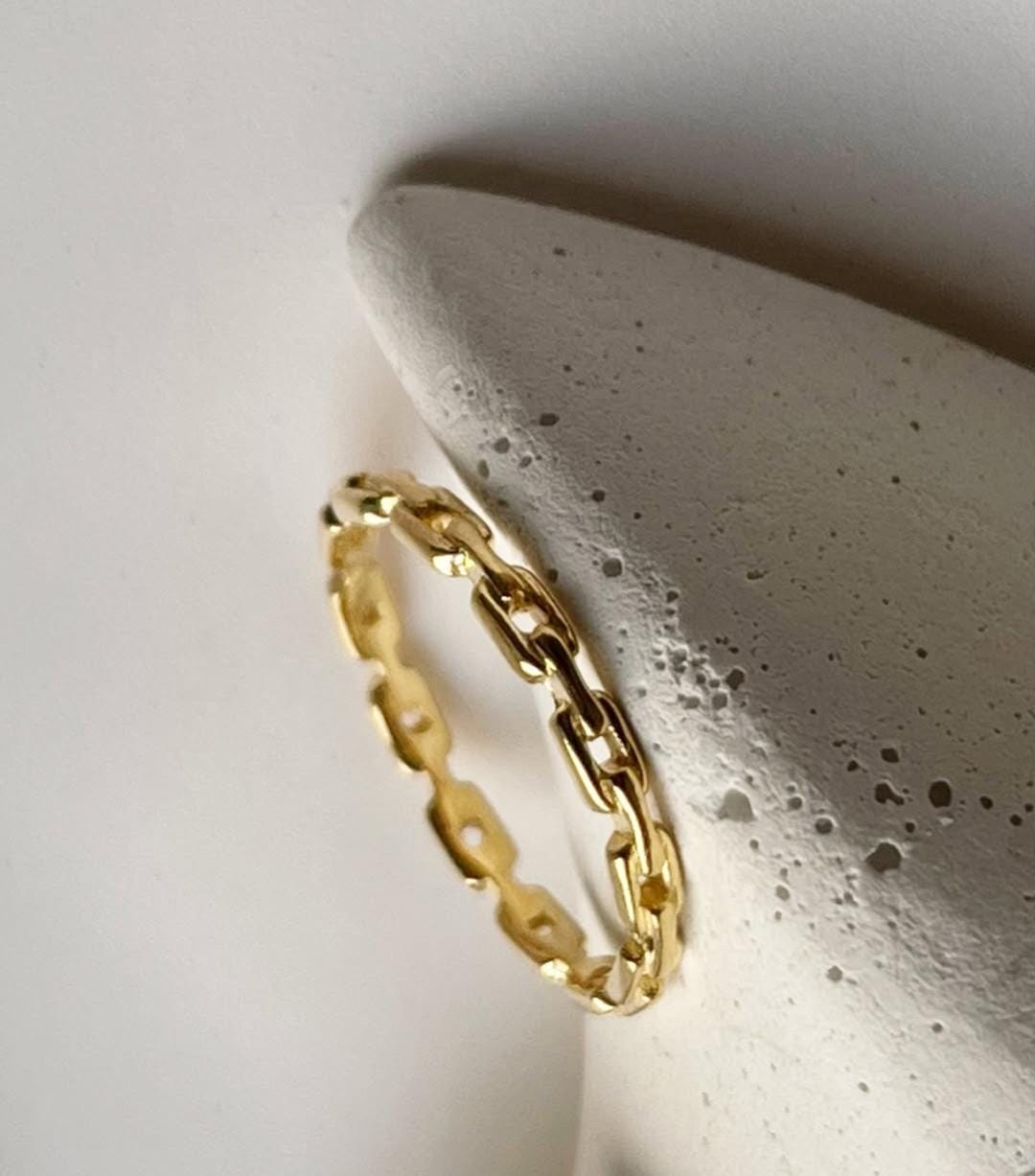 Gold vermeil thin link stack band ring displayed on a minimalist concrete stand.