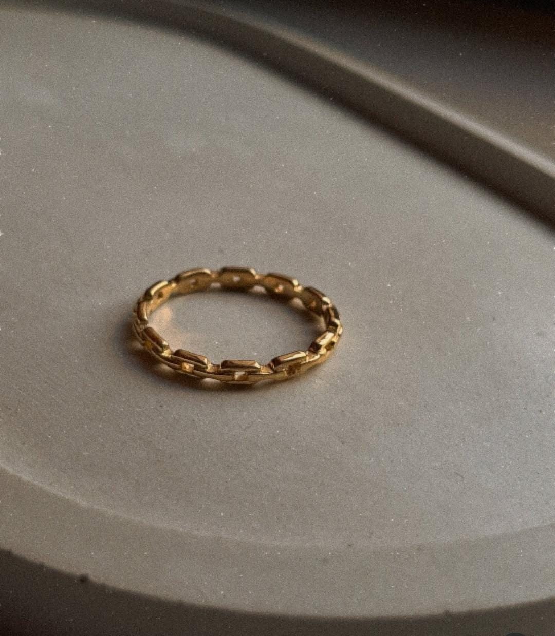 Gold vermeil thin link stack band ring on a neutral surface, showcasing its durable and elegant design.