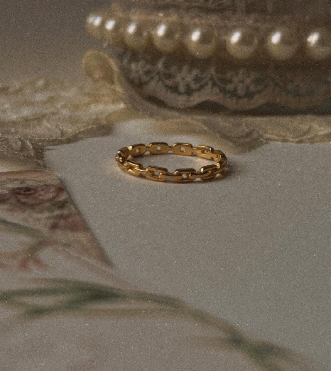 Gold vermeil thin link stack band ring displayed elegantly on vintage lace background.