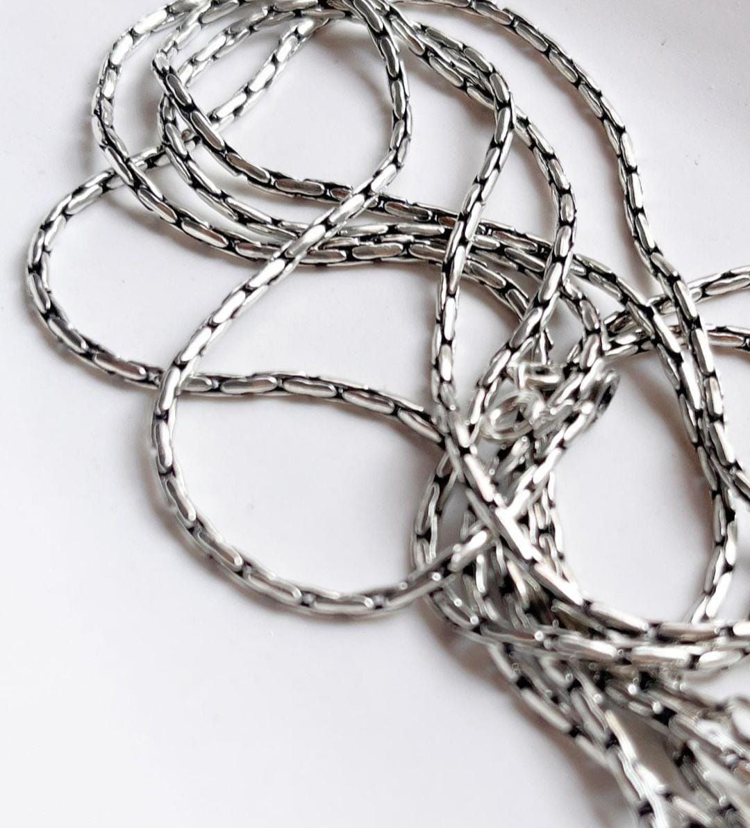 Sterling silver chain with an intricate antique pattern.