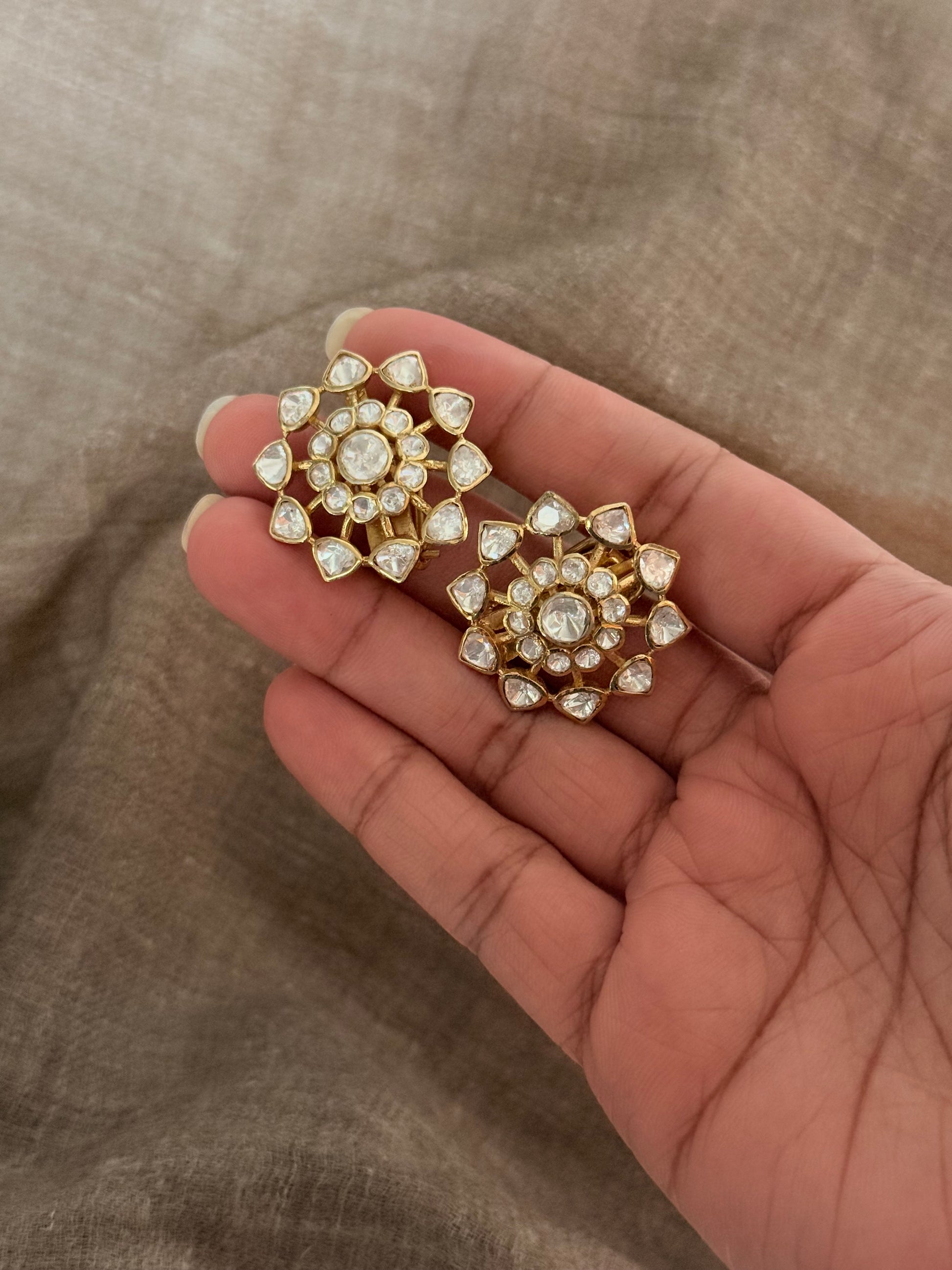Hand holding 925 Sterling Silver Gold Plated Antique Moissanite Polki Earrings with floral design.