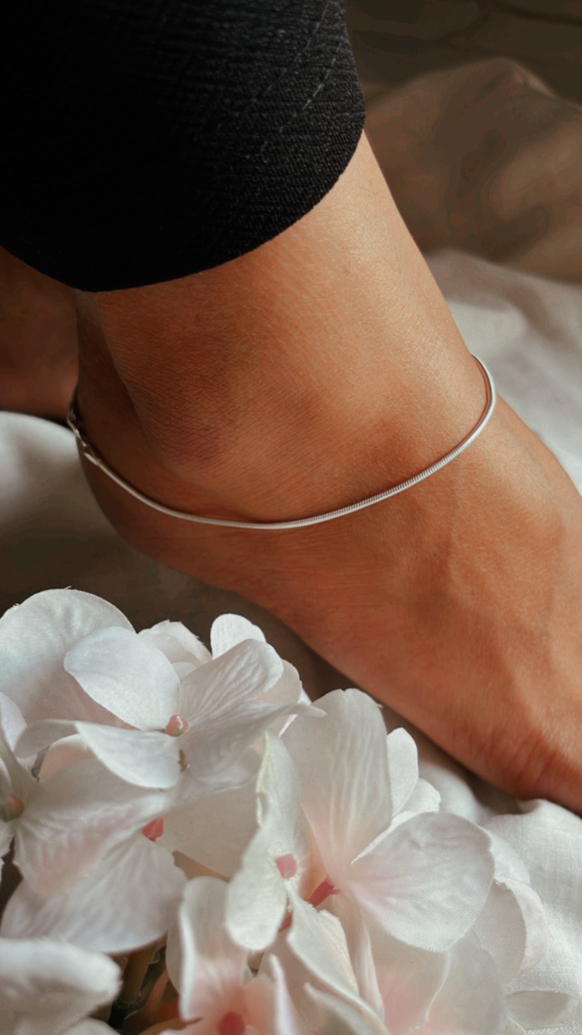 Close-up of classic snake chain anklet in polished pure silver
