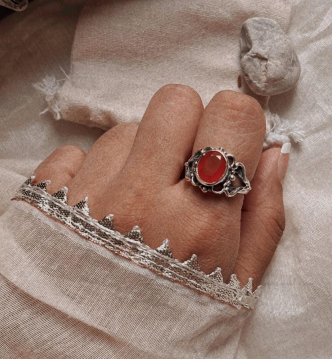 Close-up of a bold carnelian silver ring on a finger