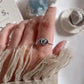 Close-up of evil eye boho silver ring with intricate design and blue topaz