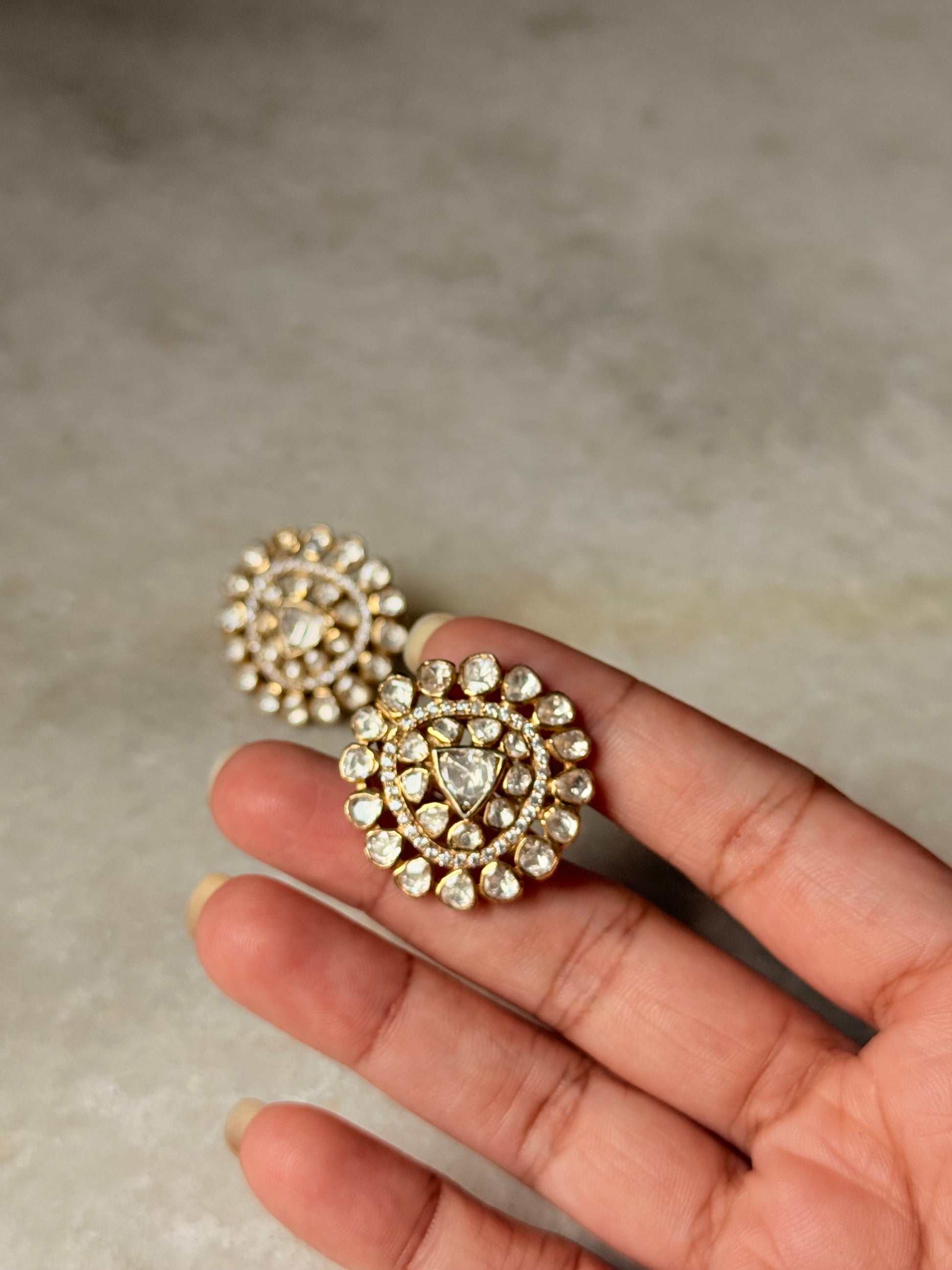 Hand holding 925 Sterling Silver Gold Plated Antique Moissanite Polki Earrings with intricate design.