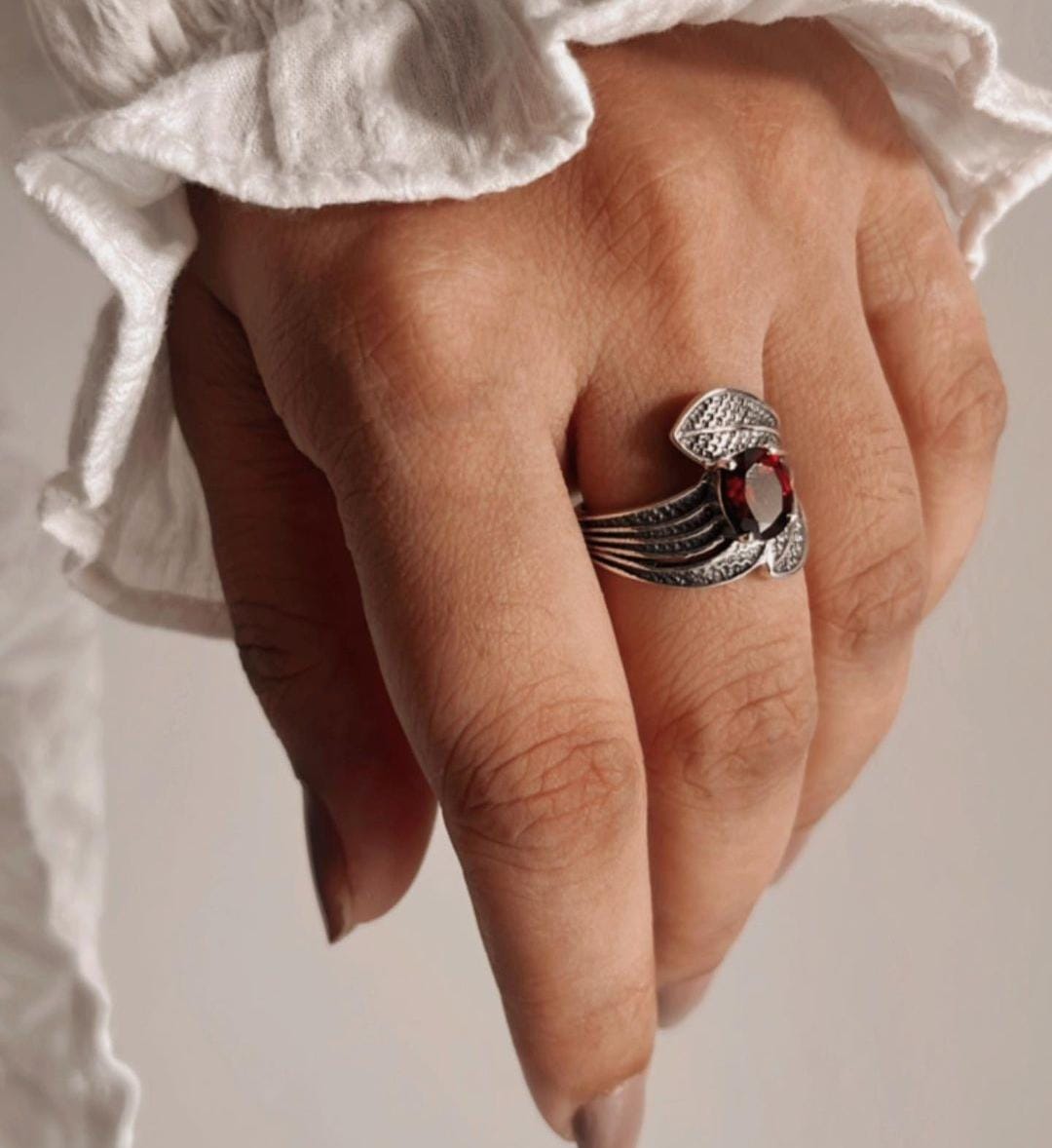 Elegant garnet stone ring with a leaf wrap pattern in silver