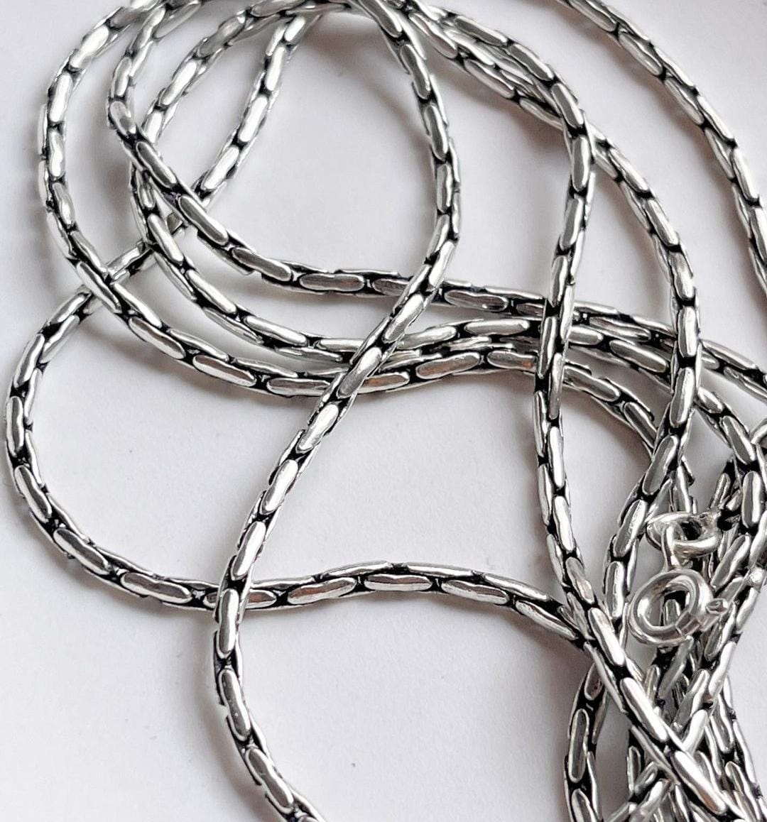 Intricate antique silver chain with unique patterns and texture.