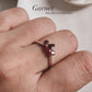 Silver ring featuring three garnet stones with pear and round cuts