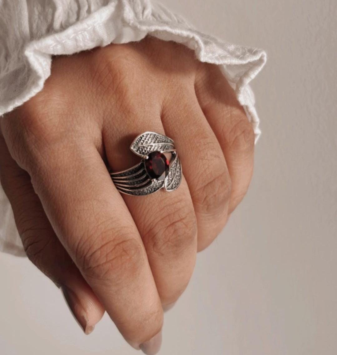 Garnet gemstone set in a silver ring with a leaf-inspired wrap