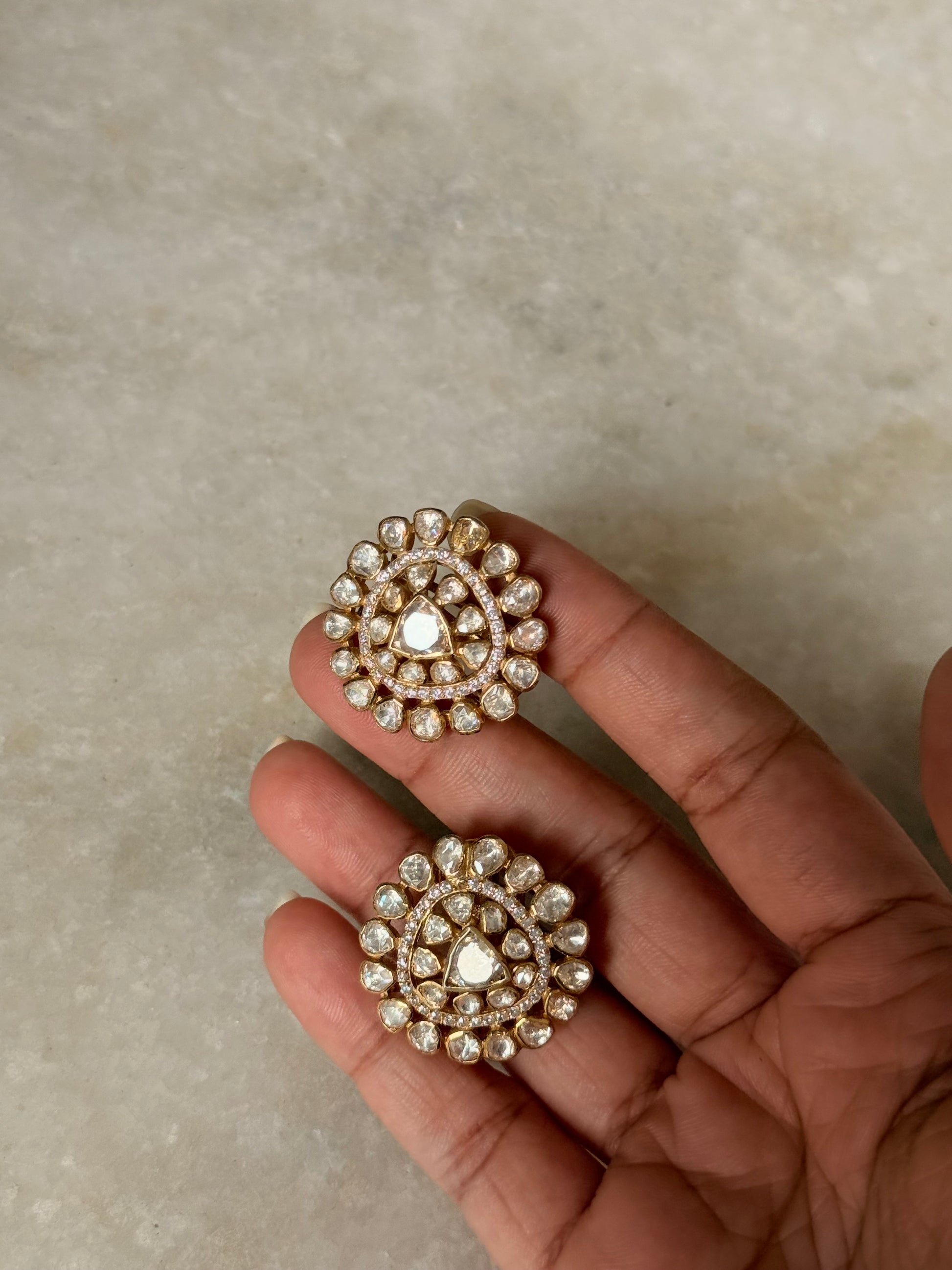 925 Sterling Silver Gold Plated Antique Moissanite Polki Round Studs Earrings held in a hand.