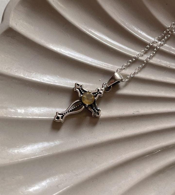 Close-up of citrine cross vintage pendant with ornate silver design