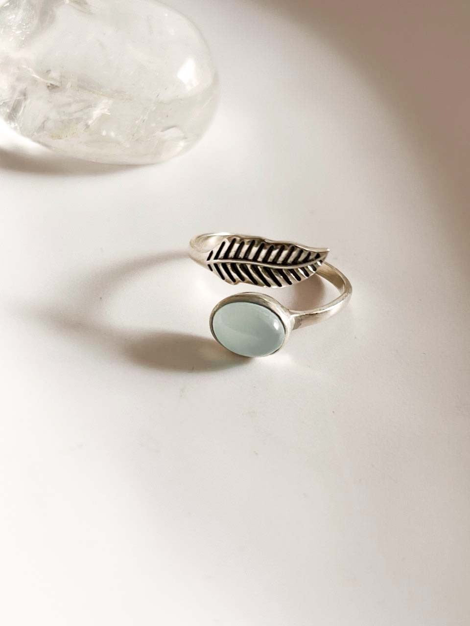 Adjustable silver ring featuring a feather design and aqua chalcedony stone.