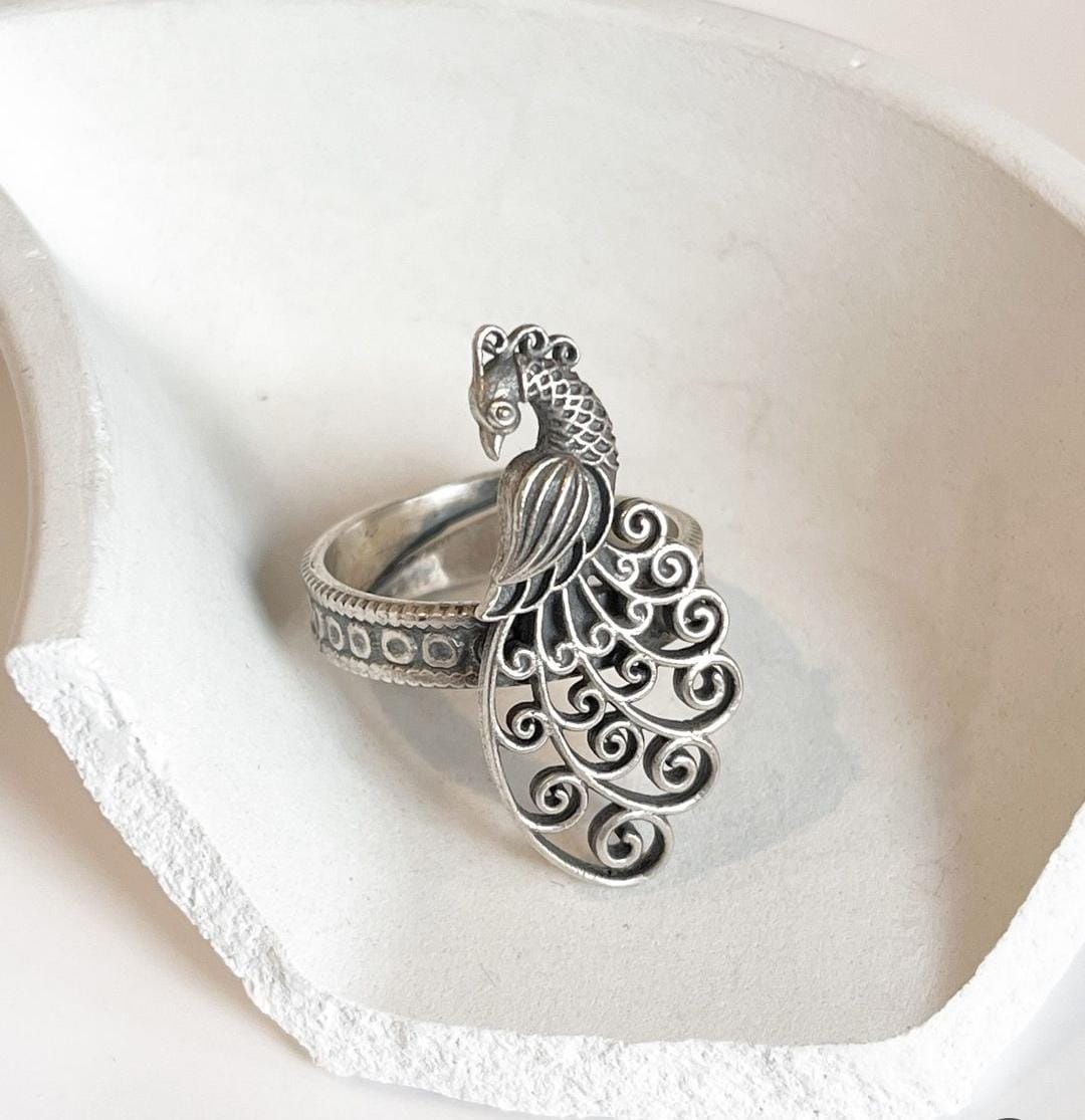 Handcrafted antique silver ring with intricate filigree and peacock design.