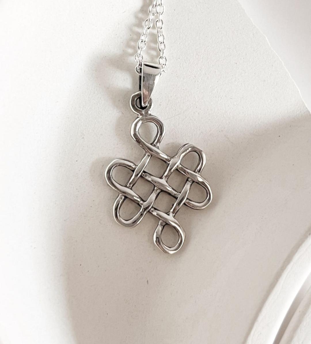 Timeless Celtic knot silver pendant with a large karma symbol.