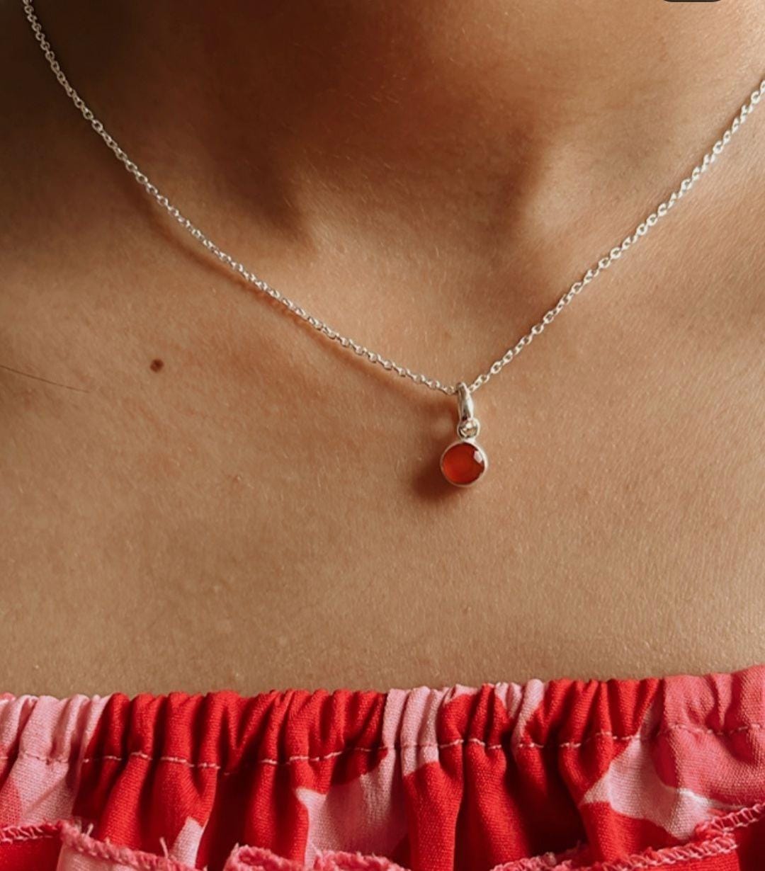 Close-up of carnelian round stone hanging from a silver pendant