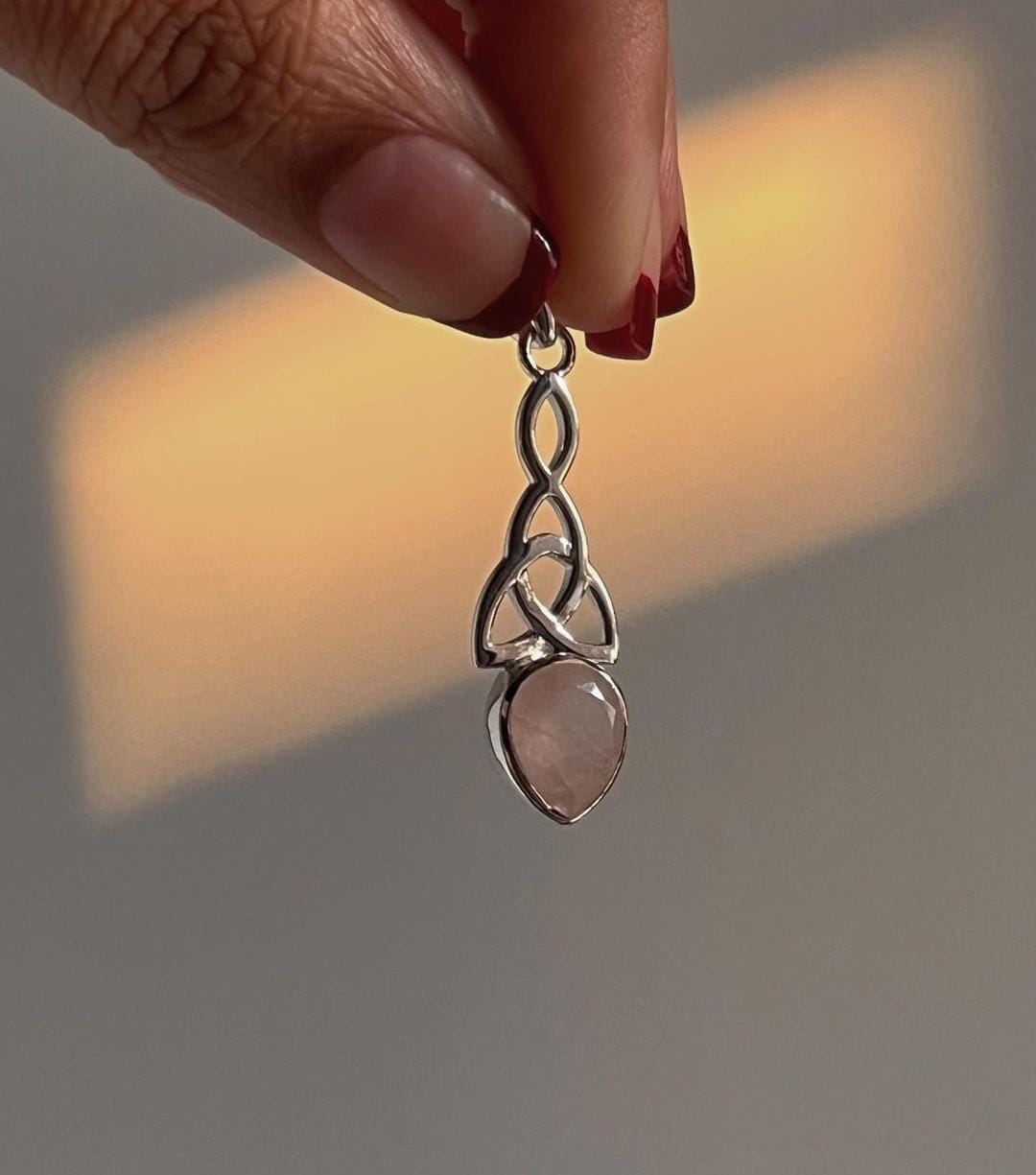 Elegant rose quartz pendant featuring a trinity knot design
