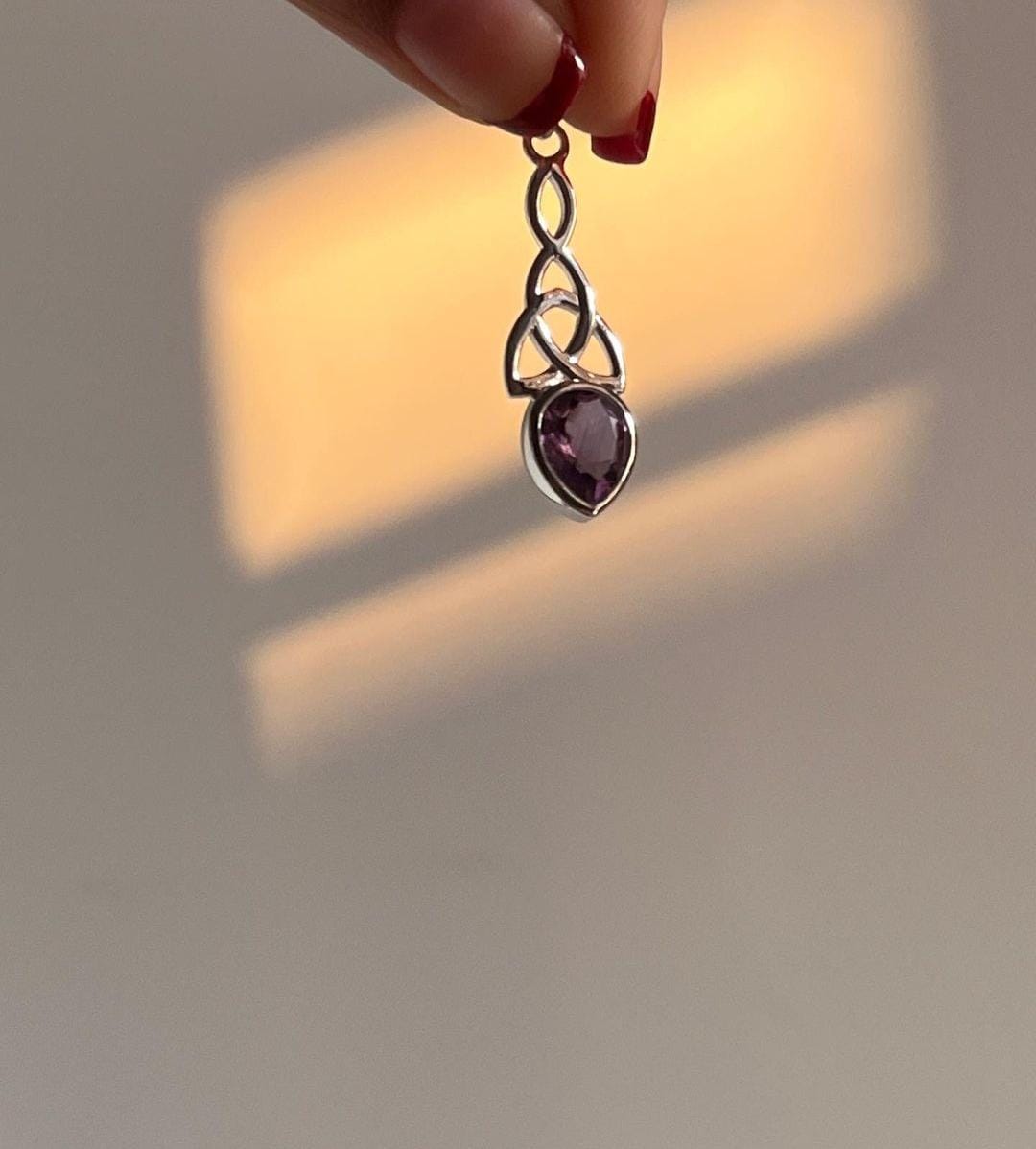 Amethyst gemstone set in a silver trinity knot pendant.