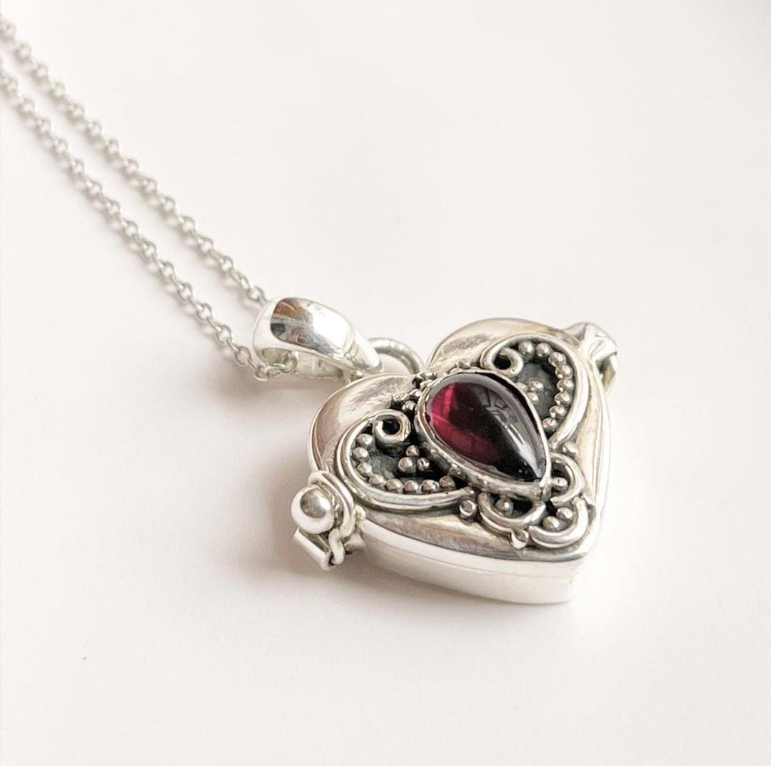Silver pendant featuring a garnet heart design with hidden storage