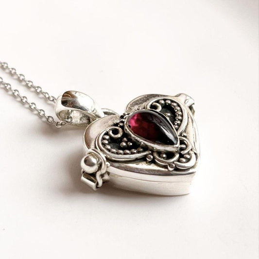 Vintage-inspired silver pendant with garnet heart and storage compartment