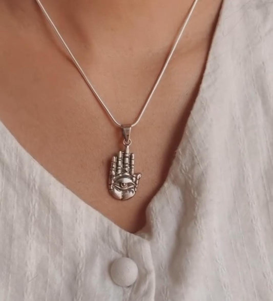 Close-up of evil eye Hamsa silver pendant symbolizing protection