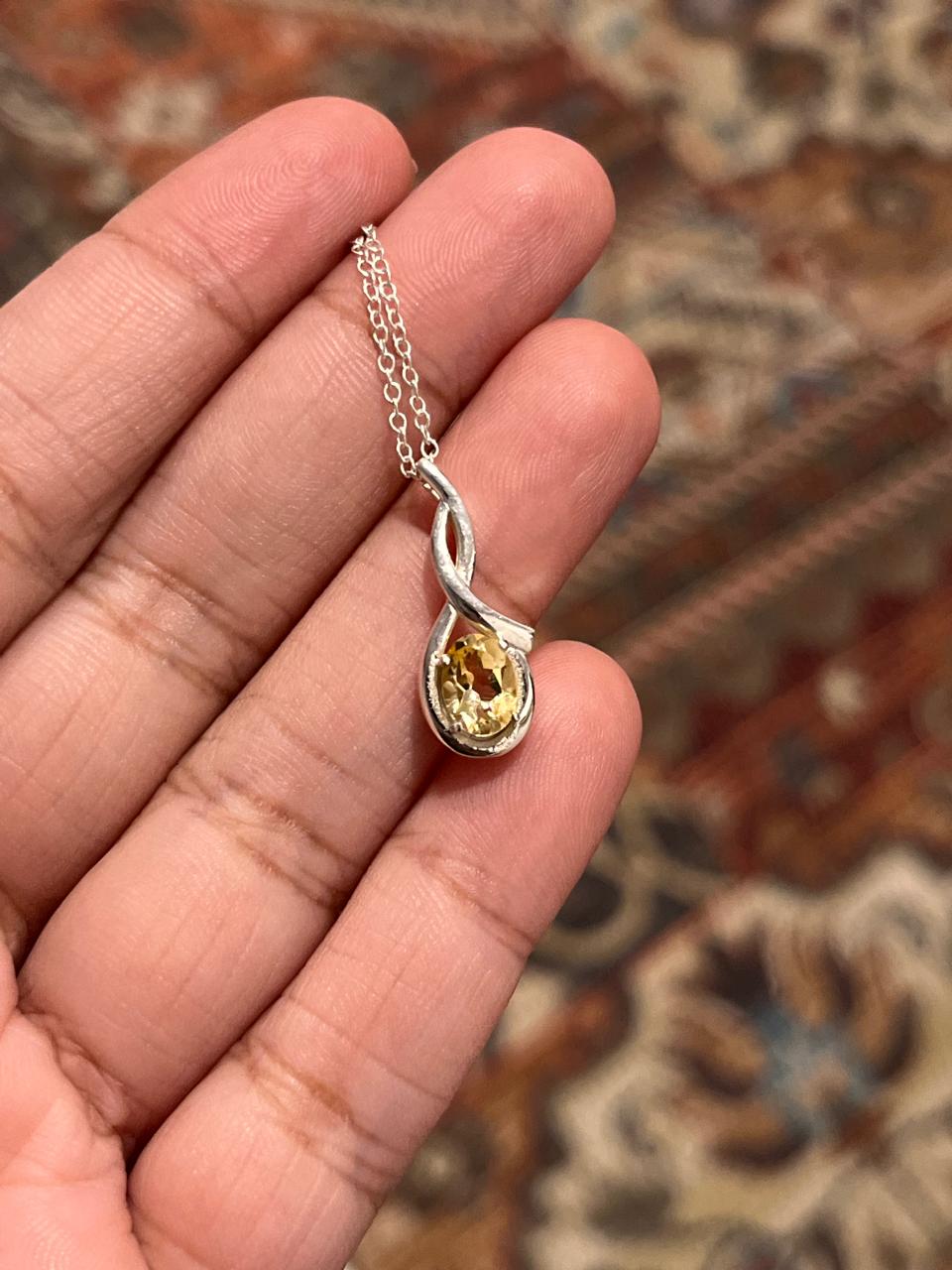 Close-up of citrine cross solitaire pendant with silver chain