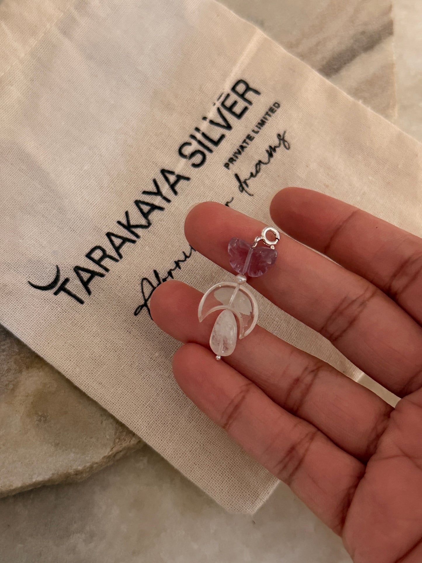 Hand holding 925 Sterling Silver Amethyst, Clear Quartz Moon & Moonstone Charms on a soft background.