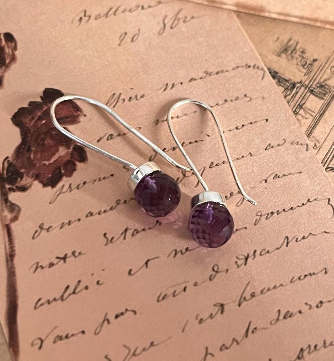 Stylish hook 925 sterling silver earrings featuring round cut amethyst gemstones.