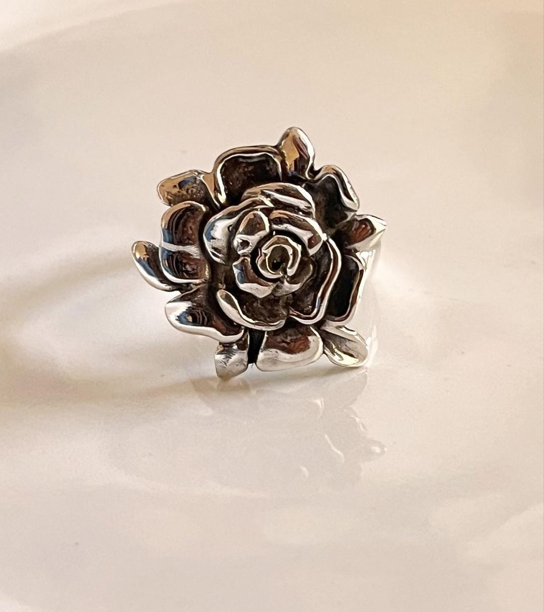 Close-up of a chunky silver ring featuring a rose motif