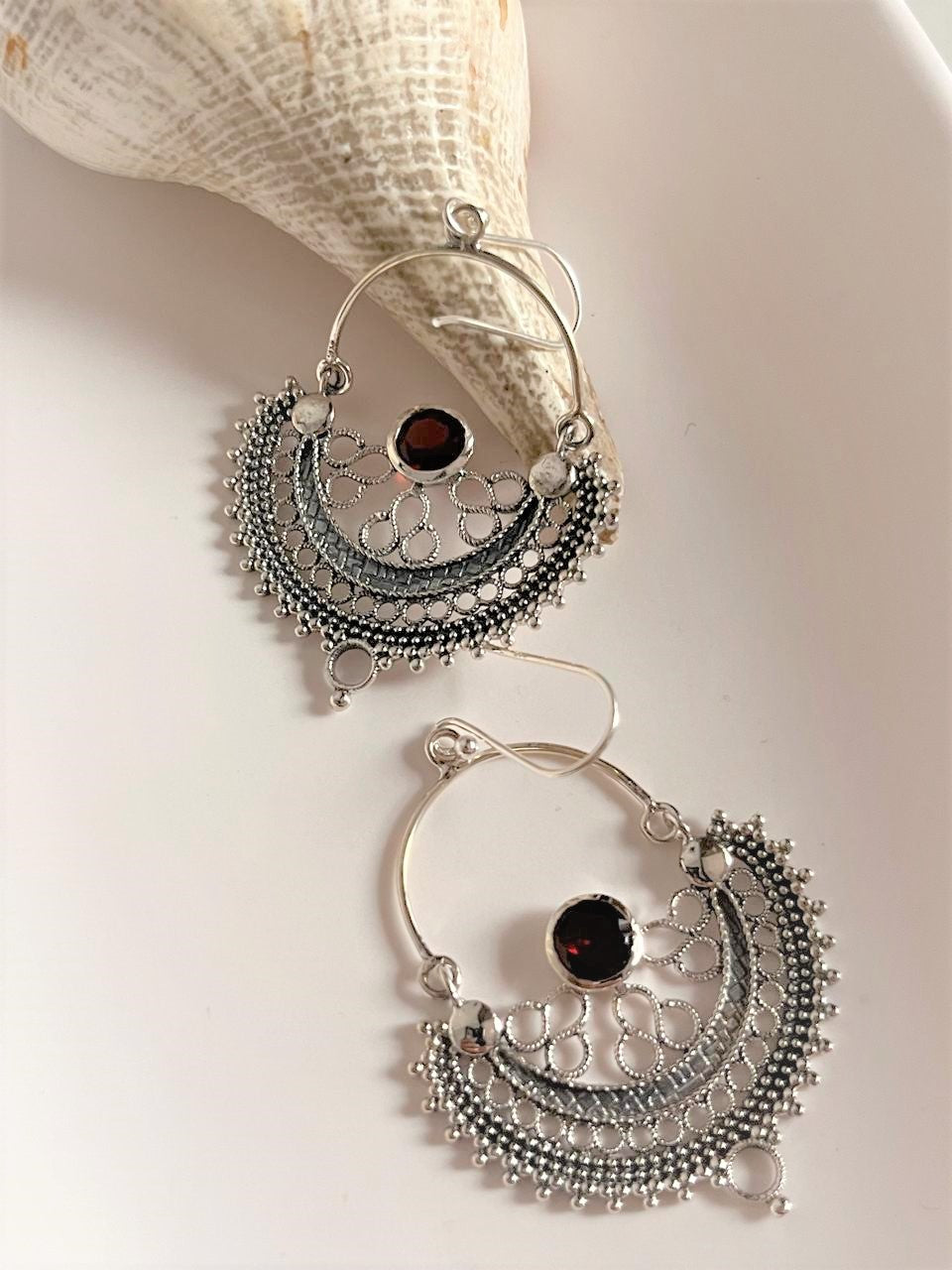 Close-up of Chandbali silver earrings featuring garnet stones