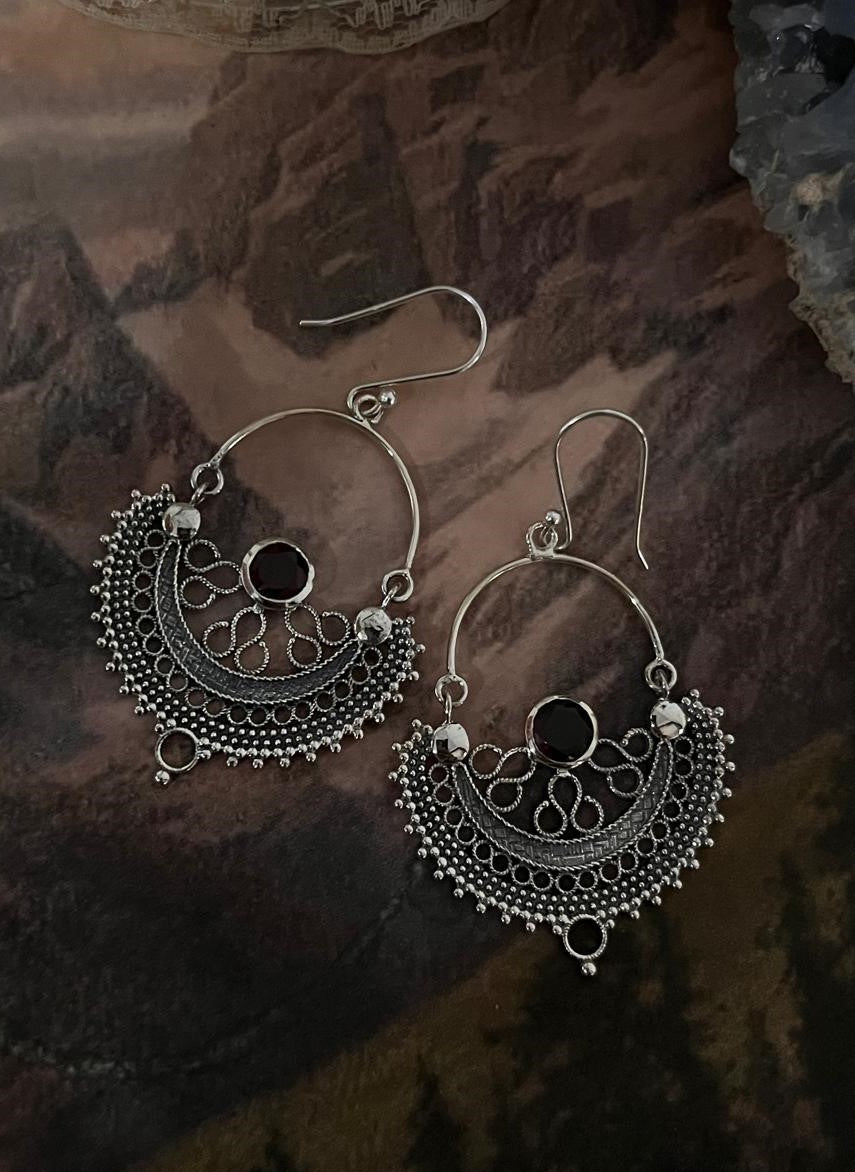 Elegant garnet gemstones set in intricate Chandbali silver earrings