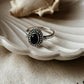 Black onyx rawa tribal silver ring on a shell, showcasing its elegant design and deep black color.