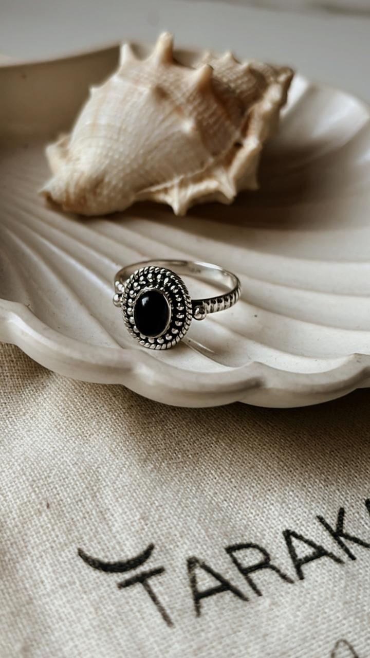 Black onyx rawa tribal silver ring on a shell, showcasing its elegant design and deep black color.