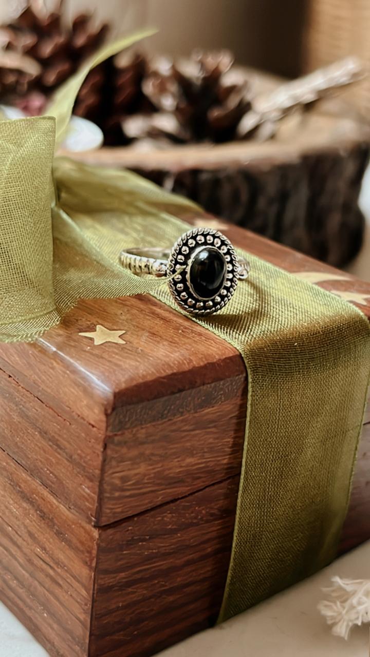 Black Onyx Rawa Tribal Silver Ring on a wooden box with a green ribbon, perfect for unique gifts and showcasing elegance.