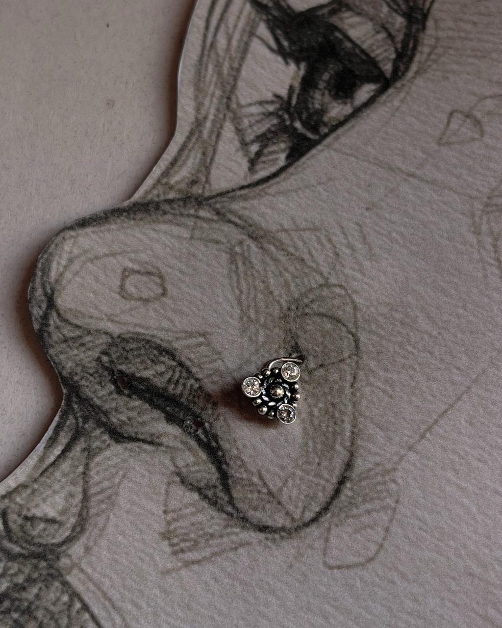 Close-up of handcrafted silver nose pin with white cubic zirconia